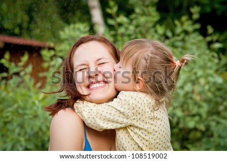 Happy young woman being kissed by a cute little girl