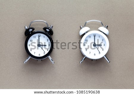 White and Black Alarm Clock on brown color background. Retro Old clasic style. Time control.