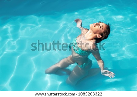 Beautiful young woman floating in pool