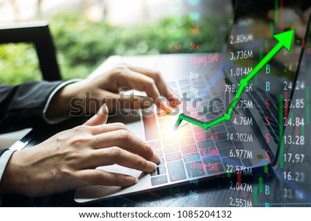Investing with laptop online.  Stock market concept gain and profits with faded candlestick charts.