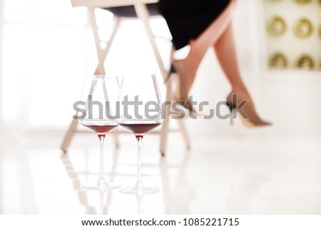 glasses of red wine with girls feets on background