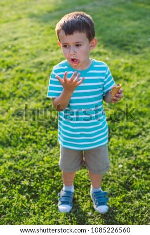 Cute smeared little boy eating ice cream