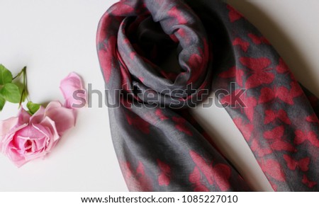 Grey beautiful scarf with pink butterfly print on white background with a rose.  Royalty-Free Stock Photo #1085227010