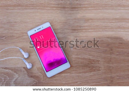 I miss you text message in blue background with white phone and earphone on wooden table.