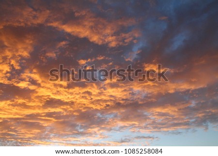 Orange coloured fragmented clouds, shot around sunset time. The sky is still a bright blue, creating a high contrast beautiful summer picture.