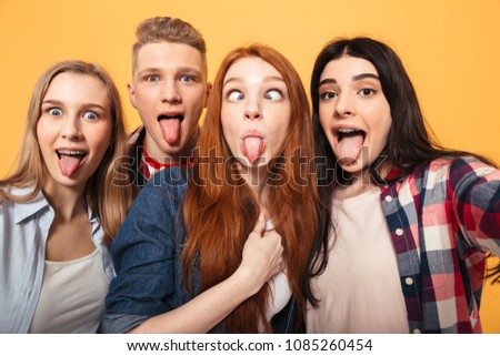 Group of funny school friends taking a selfie while having fun together over yellow background