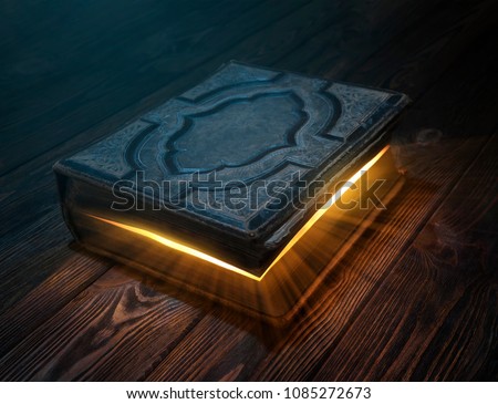 Old magic book on wooden table with light rays coming out form the inside