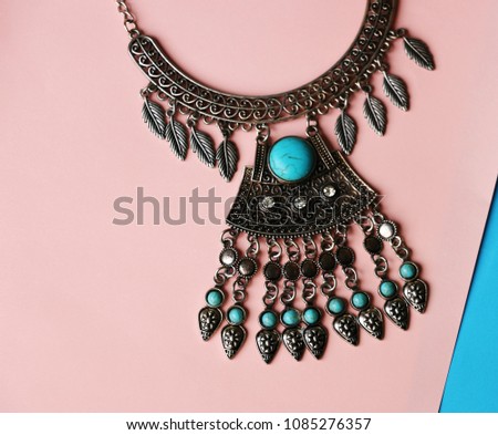 Bohemian style necklace with turquoise gemstones on abstract background. Royalty-Free Stock Photo #1085276357