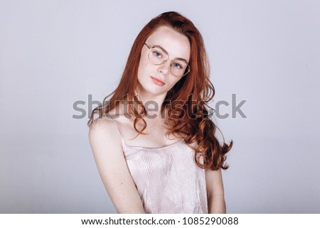 Close up portrait of ginger freckled caucasian girl posing in studio depressed and have sad emotions in eye glasses