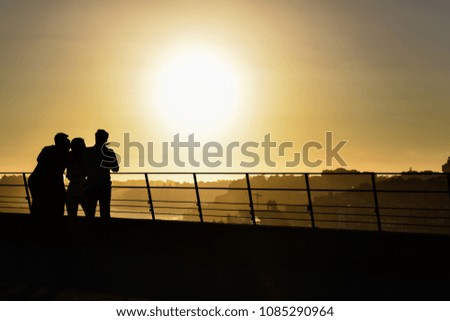 Silhouette of some young people watching the city at sunset