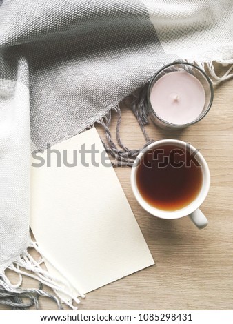 Flat lay stylish mockup cozy photo with a grey candle, blank greeting card, a cup of tea and plaid. Feminine photo for blog and website.