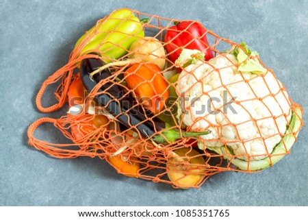 String bag with various fresh vegetables on blue textured background. Organic eco bio products from farm. New harvest. Ingredient in healthy, dietary and vegetarian food