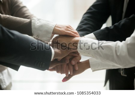 Diverse multiracial business team holding stacked pile of hands together promising help loyalty support, engaging in teambuilding, united at motivating training, coaching concept, close up view Royalty-Free Stock Photo #1085354033