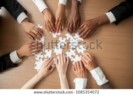 Hands of diverse people connecting puzzle together on office desk, multi-ethnic team engaging in finding best business solutions for successful teamwork, teambuilding unity concept, top close up view Royalty-Free Stock Photo #1085354072