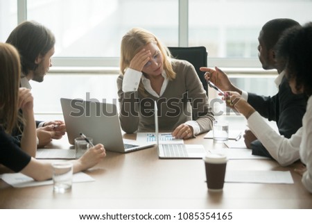 Stressed exhausted businesswoman tired of disrespect or discrimination at multiracial meeting, disappointed depressed woman boss feeling sad about colleagues criticizing at diverse group briefing Royalty-Free Stock Photo #1085354165