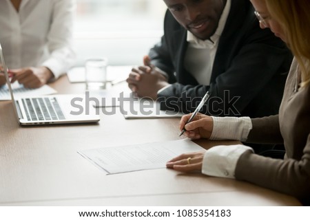 Businesswoman signing business document at meeting with african partners, satisfied client customer agreeing to put signature on contract agreement buying services or taking bank loan, close up view