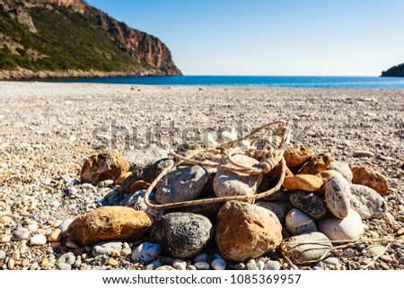 Beach stone fireplace with rope. Sea water with mountains rock in the background. Vlychada Beach Laconia Peloponnese Greece.