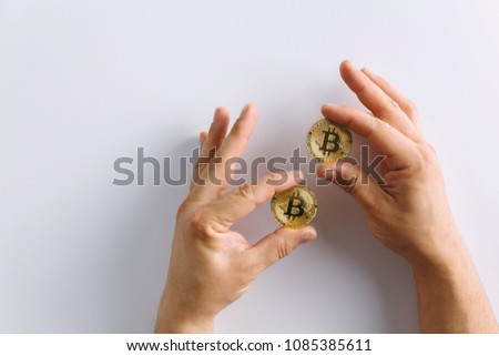 A hands holding a two gold coins, Bitcoin cryptocurrency. The hand is making a gesture.White background.