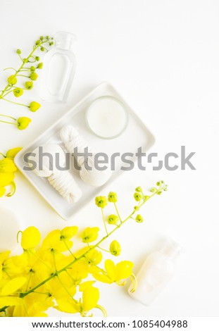 Bright spa background: candles and thai massage herbal bags with bottles and yellow flowers on white. Health, skin treatment concept Royalty-Free Stock Photo #1085404988