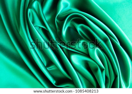Beautiful smooth elegant wavy green satin silk luxury cloth fabric texture, abstract background design. Card or banner.