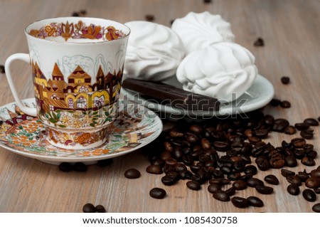 bright cup with coffee beans and sweets on a wooden table close-up