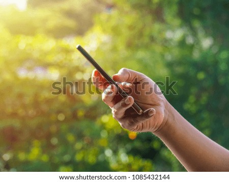 Close up of a man's hand using mobile smart phone outside on sunny summer day with copy space.