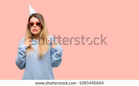 Young woman celebrates birthday happy and surprised cheering expressing wow gesture, pointing with finger