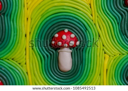 A red mushroom with white spots. Children's creativity. Picture of colored clay handmade. Macro photo.