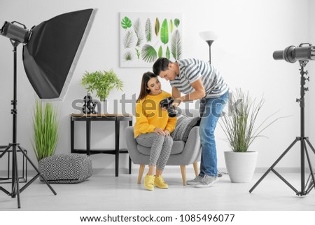 Photographer and model discussing picture on camera display in professional studio