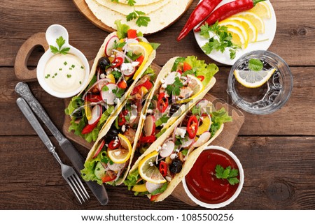Traditional Mexican tacos with meat and vegetables on wooden background. top view.