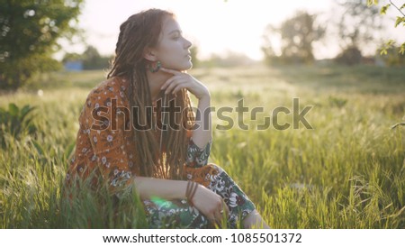 beautiful hippie woman with dreadlocks in the woods at sunset having good time outdoors