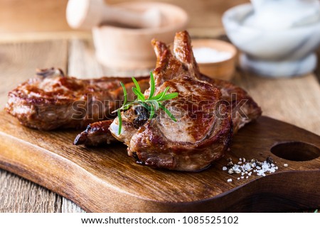 Roasted veal chops with fresh herbs on rustic wooden cutting board, pan seared steak dinner Royalty-Free Stock Photo #1085525102