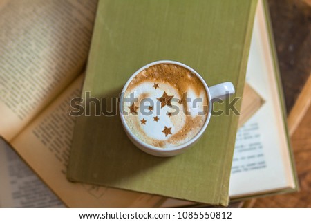 Cappuccino in a cup with a picture of stars and books