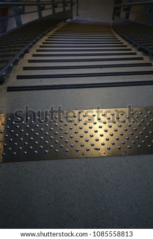 Close up view from the top of a metallic staircase in a french public hall. Pattern of lighted steps. Rectangular surfaces with points. Modern architectural image. Abstract perspective image. 