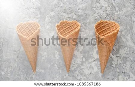Three empty waffle horns on a concrete background. Top view, creative background, minimalist trend
