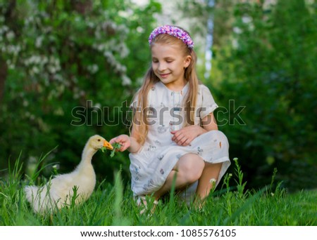 Pretty girl feeding duckling with grass