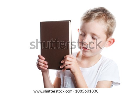 small boy looks at closed book, portrait on isolated white background, schoolboy with book in hands