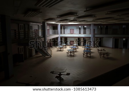 Light from skylight into common area of abandoned state prison cell block. Royalty-Free Stock Photo #1085613473