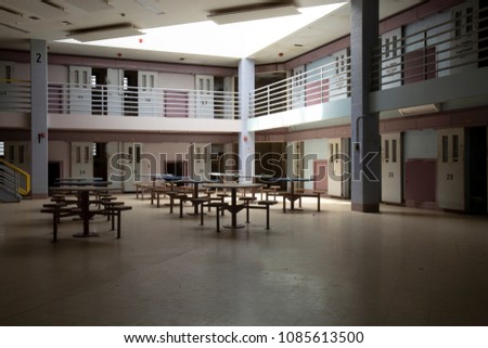 Interior of cell block in abandoned State Correctional Institution, or jail., common room with jail cells. Royalty-Free Stock Photo #1085613500