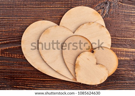 Collection of plywood hearts for decoupage. Wooden heart tags on brown wooden table, top view.