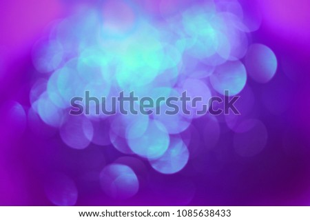 Bokeh lights background in ultraviolet, turquoise and lilac colors. Festive background. Big circles on a bright background. Magic glowing effect.