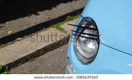 headlight of car decorated with black bands to simulate human lashes