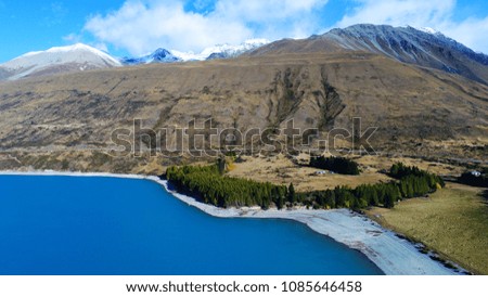 Aerial view of Lake Pukaki in South New Zealand showing incredibly blue turquoise water and mountain terrains landscape.