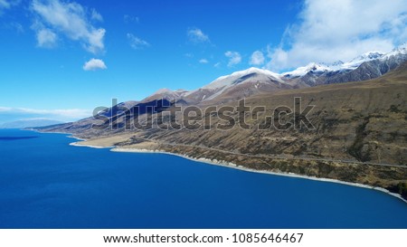 Aerial view of Lake Pukaki in South New Zealand showing incredibly blue turquoise water and mountain terrains landscape.