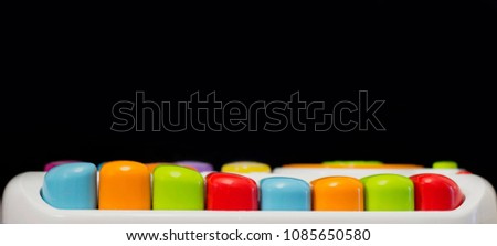 baby toy piano with colored keys on dark background