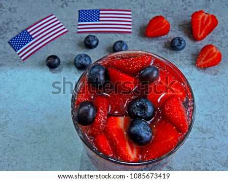 A festive lemonade with strawberries and blueberries on Independence Day. Soda in patriotic style. American flags.