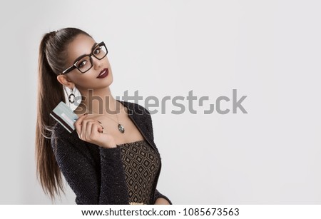 Banking concept. Smiling young woman dark ponytail hair style holding bank credit card isolated portrait over white gray background wall. Multicultural ethnic model mixed race indian african american.