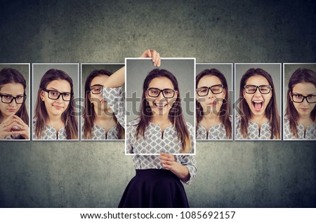 Girl holds and changing her face portraits with different expressions. Woman expressing different emotions Royalty-Free Stock Photo #1085692157