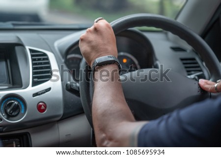 back side of aman driving in a car and smart watch in his hand
