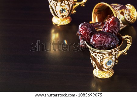 Still life with dates and golden Traditional Arabic coffee set with mini cup. Dark background. Copy space.
